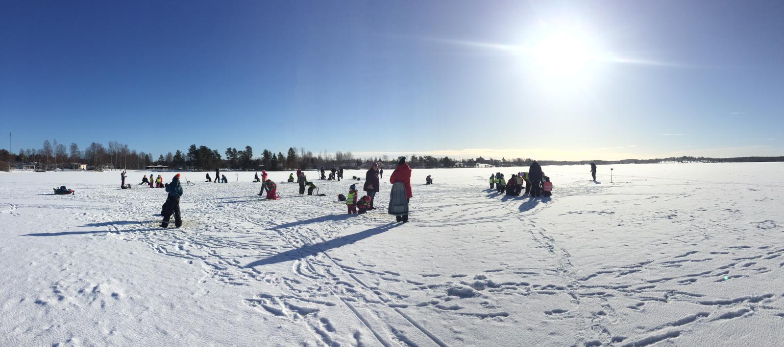 Foto: frusen sjö med snö och lekande barn.