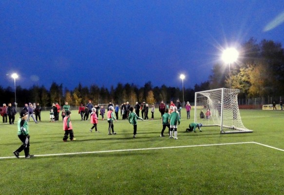 En kvällsmatch på konstgräsplanen med små barn som spelar.