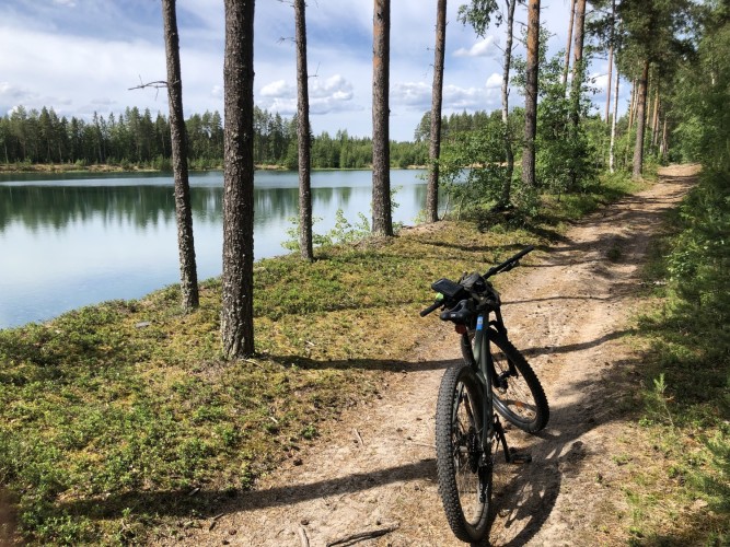 en cykel står vid en skogsväg nära vatten
